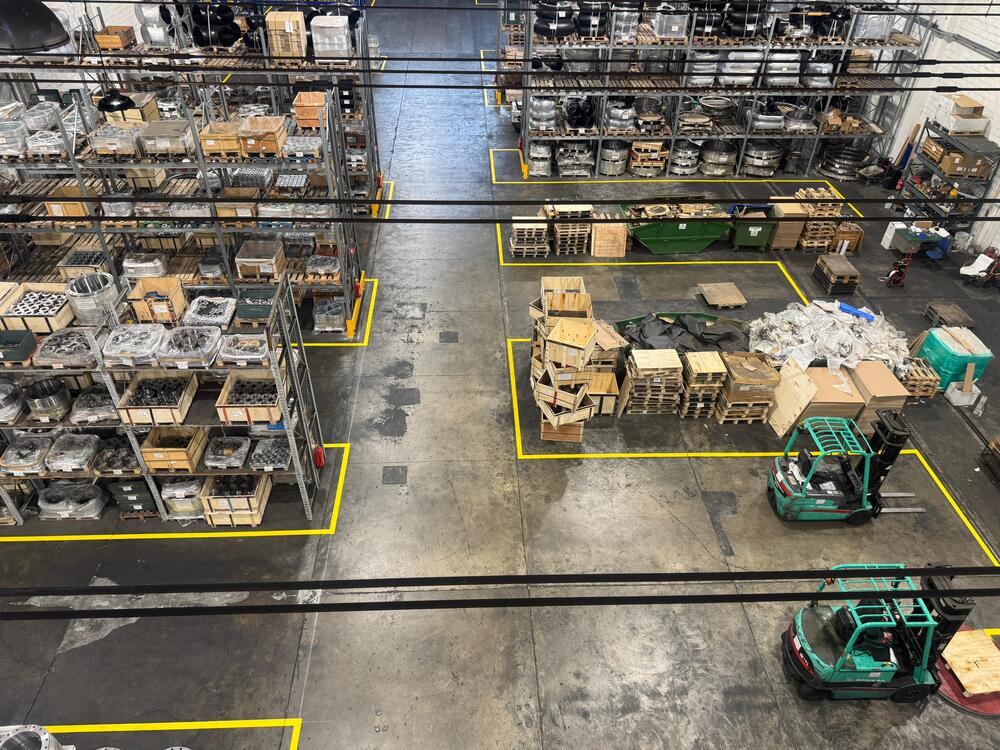 Industrial warehouse with forklifts, pallets, shelving, and packaging materials demonstrating responsible reuse and inspection of transport packaging at Slobrides d.o.o.