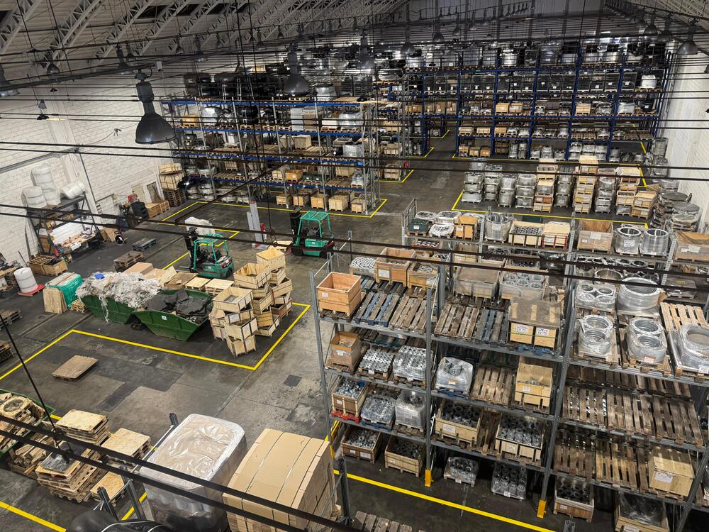 Organized industrial warehouse with machinery, metal components, and storage zones illustrating reusable packaging and circular economy practices at Slobrides d.o.o.